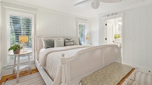 A bedroom with a bed, a bedside table with a lamp, and a window with blinds.