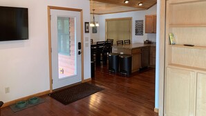 A modern kitchen with wooden cabinets, a dining area with chairs, a built-in bench, and a TV mounted on the wall. - Gorgeous New 2BR Family Beach Retreat with Paddle Boat (Sarona)