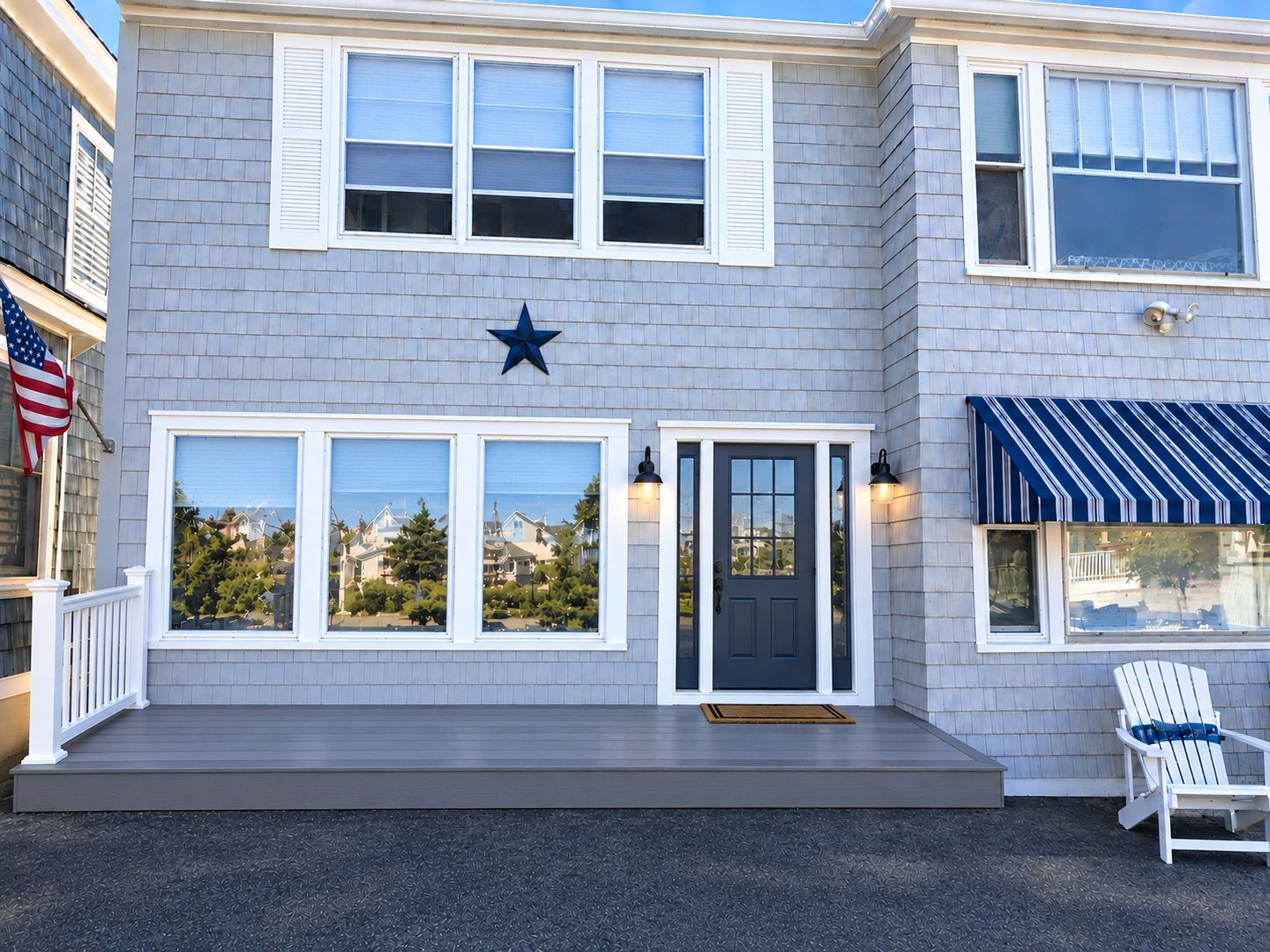 A two-story building with a dark front door, a star decoration above the entrance, and a small porch with a chair.