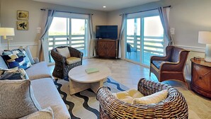 A spacious living room with a sofa, two wicker chairs, a coffee table, and a television.