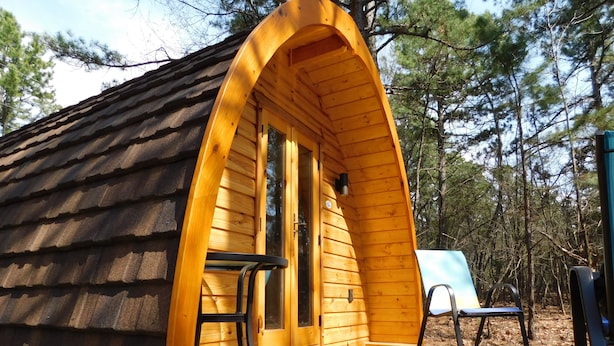 Uma cabana de madeira com telhado inclinado, uma porta e um banco na parte externa.
