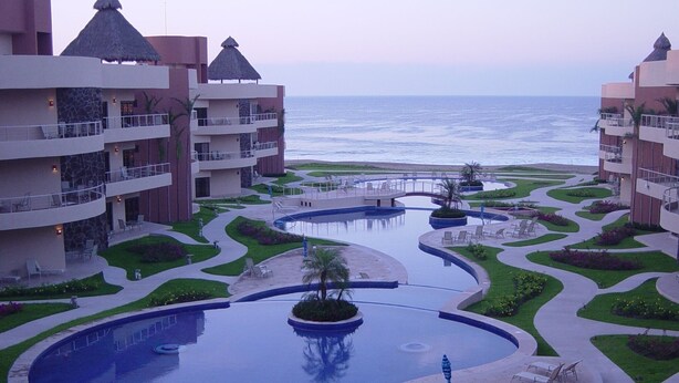 Un resort con una piscina grande, varios balcones y vista al océano.