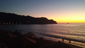Una playa al atardecer con tiendas de campaña y un mar tranquilo.