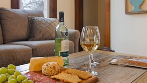 Un tavolo con una bottiglia di vino, un bicchiere, formaggio, uva, crackers e una rivista.
