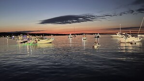 Una marina con imbarcazioni ormeggiate di notte, acqua calma e un cielo al tramonto.