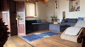 Un salon chaleureux avec un plancher en bois, un canapé, un fauteuil et une petite table agrémentée de plantes.