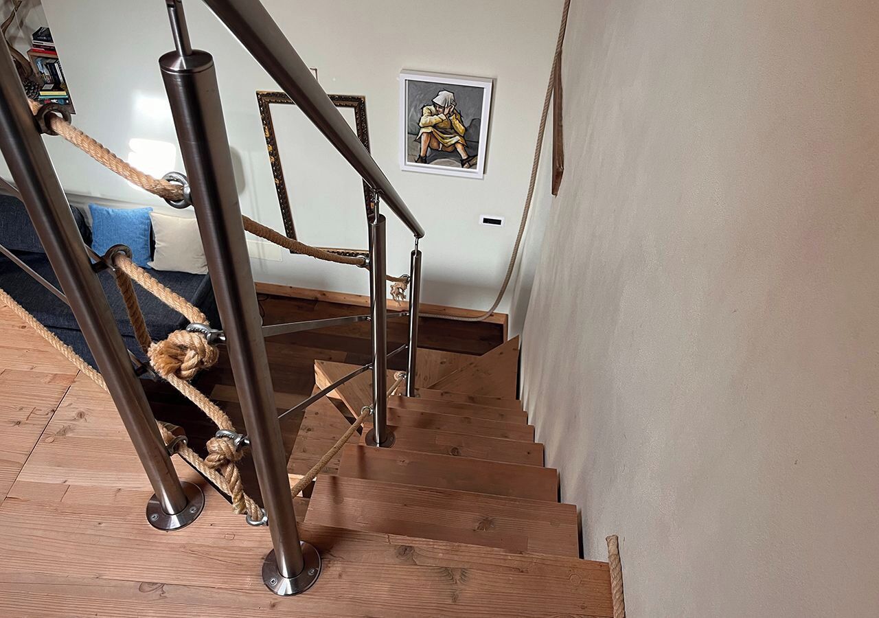 A wooden staircase with metal handrails and a rope barrier.