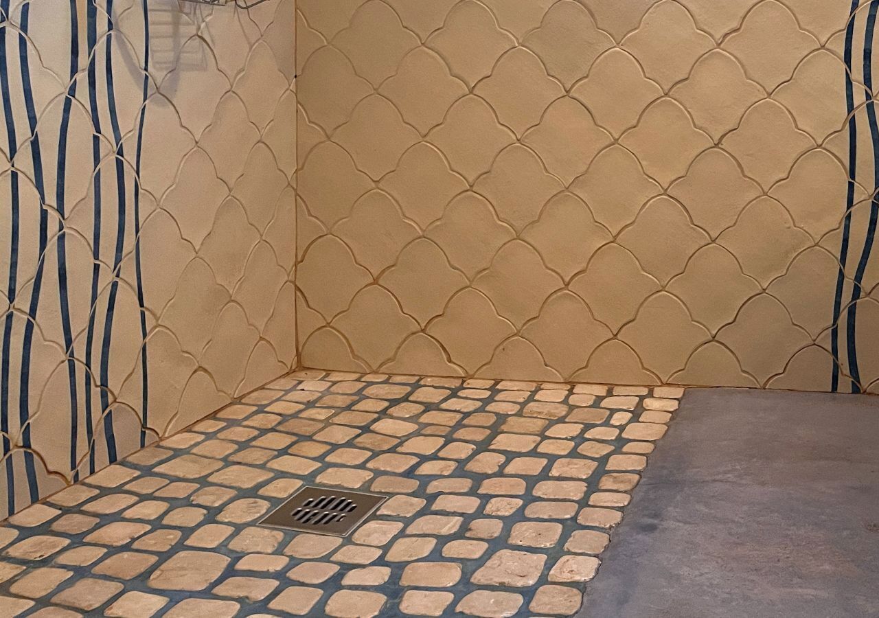 Un baño con piso de baldosas, un desagüe y una pared con diseño ondulado.