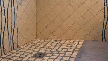 Un baño con piso de baldosas, un desagüe y una pared con diseño ondulado.