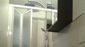 A bathroom with a glass-enclosed shower, a toilet, and a sink with a mirror above. - Independent studio in the center (bracciano)