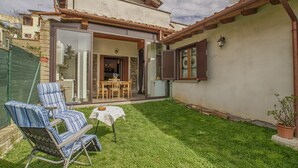 A house with a patio area featuring two striped chairs and a small table. - Independent studio in the center (bracciano)