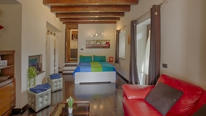 A bedroom with a bed, a red leather sofa, and a wooden ceiling. - Independent studio in the center (bracciano)