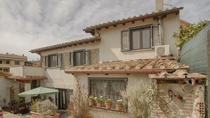 A two-story house with a tiled roof, a chimney, and a small garden with potted plants. - Independent studio in the center (bracciano)