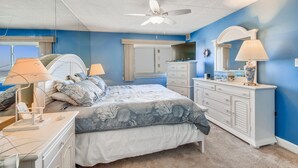 Un dormitorio con cama, cómoda y ventilador de techo.