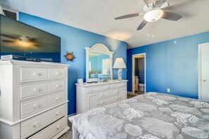 Ein Schlafzimmer mit einem Bett, einem Schminktisch, einer Kommode und einem Deckenventilator.