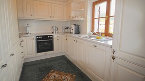Cuina amb armaris blancs, forn negre, un rentapeus i una finestra amb vista.