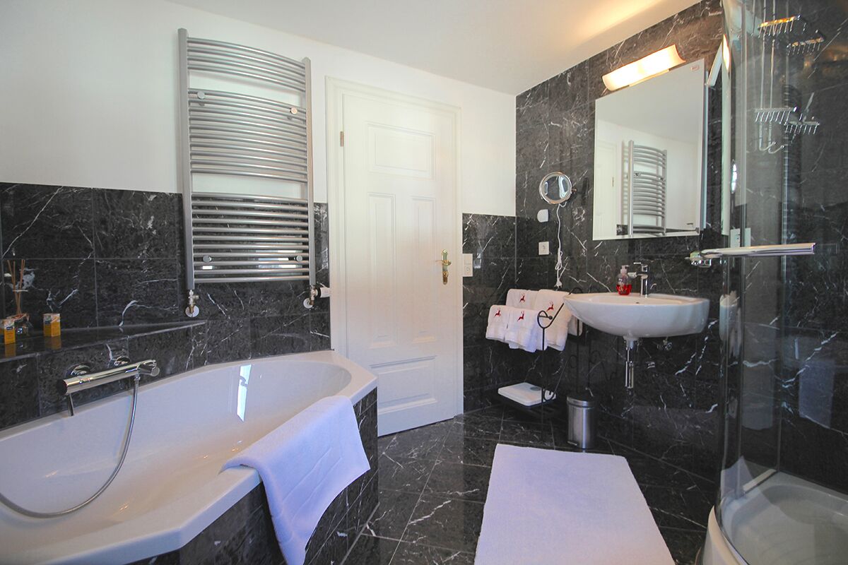 A modern bathroom with a bathtub, a sink, a glass shower enclosure, and a large mirror.