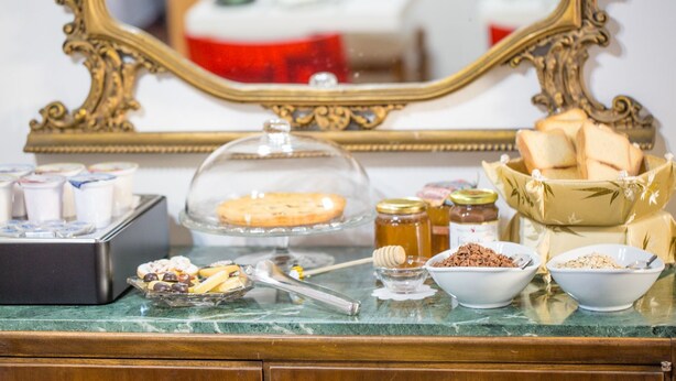 A buffet table with various food items, including a covered dish, jars of honey, and bowls of nuts and seeds.