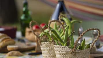 Two woven baskets with green plants, a bottle, and bread on a table.