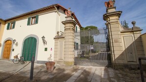 A building with a large wooden door, green shutters, and a metal gate with statues.