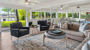 A spacious living area with a sofa, chairs, a coffee table, and a view of a lake.