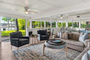 A spacious living area with a sofa, chairs, a coffee table, and a view of a lake.