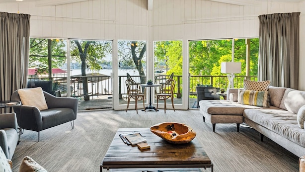 A spacious living room with a large window, a ceiling fan, and a wooden coffee table.