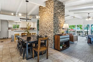 Une cuisine spacieuse avec des meubles blancs, un mur dâaccent en pierre et un coin repas comprenant une grande table et des chaises.