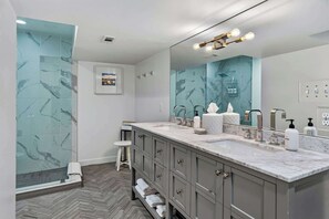 Une salle de bain moderne dotĂ©e dâun grand miroir, de deux vasques et dâun espace douche.