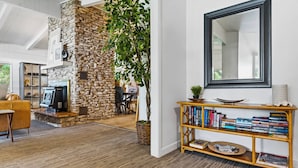 A modern living room with a stone fireplace, a bookshelf, and a large mirror.