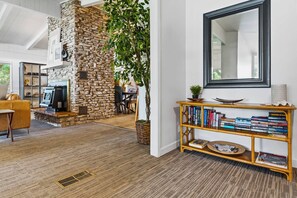 A modern living room with a stone fireplace, a bookshelf, and a large mirror.