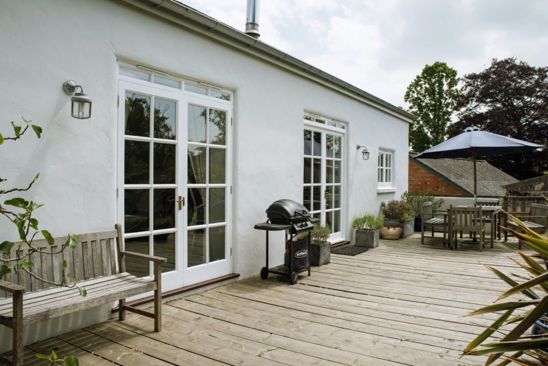 A white building with large windows and a wooden deck.