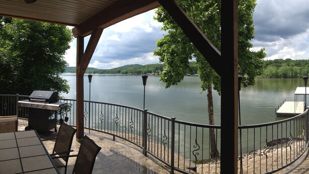 A covered patio with a view of a lake, a grill, and a dock. - Great lakefront Log Home  (Roach)