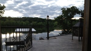A concrete pathway leading to a dock by a calm lake, surrounded by trees and a gazebo. - Great lakefront Log Home  (Roach)