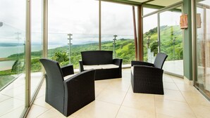 Un balcon doté de meubles en osier et offrant une vue sur un paysage verdoyant.