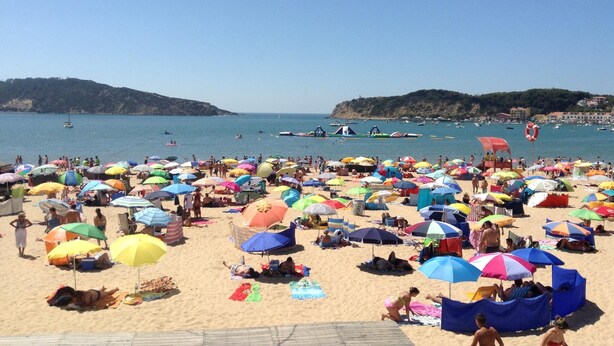 Una spiaggia affollata con molti ombrelloni colorati e persone che si rilassano.