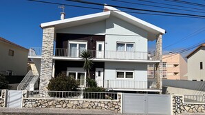Un edificio a due piani con facciata in pietra, un balcone al piano superiore e un ingresso carrabile.