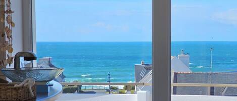 A balcony with a view of the sea, a metal bowl, and a wicker basket.