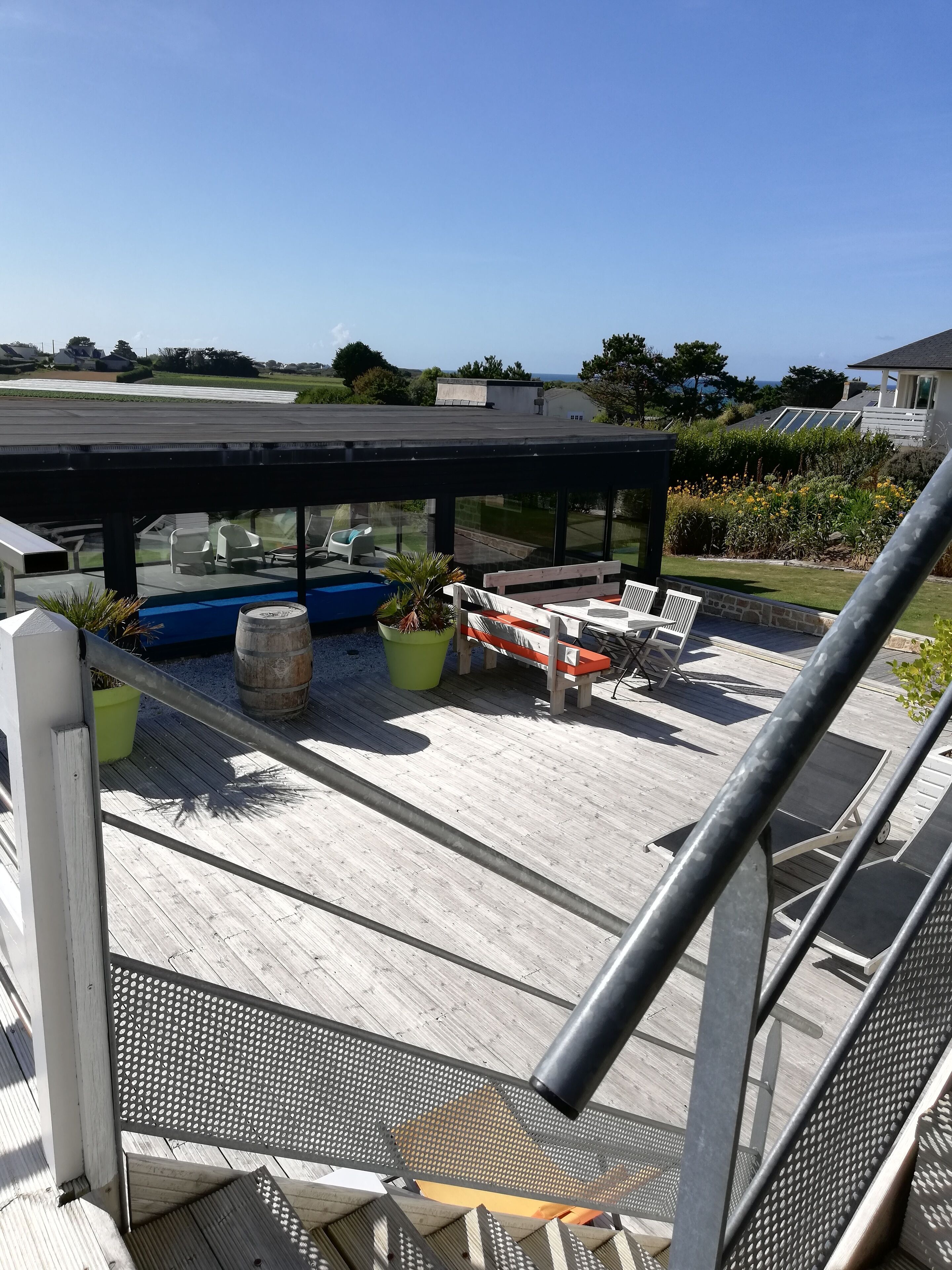A covered outdoor deck with seating and a view of the surrounding landscape.