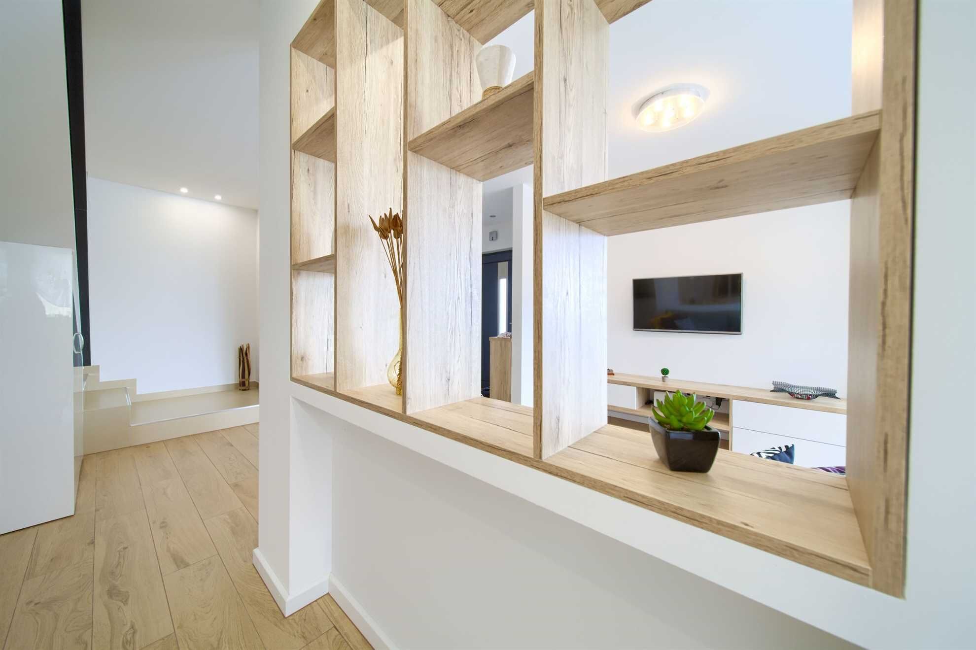 A modern interior with a wooden shelf unit, a flat-screen TV, and a potted plant.