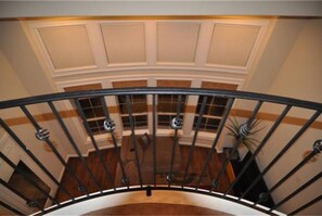 Staircase leads to an upper floor with decorative paneling and windows offering a view of the interior space below.