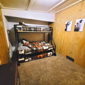 A bunk bed with a plaid bedspread and a small rug on the floor.