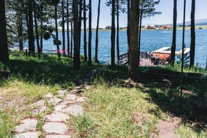 A stone pathway leading to a lakeside area with a wooden deck and seating.