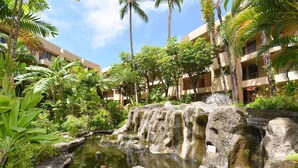 A hotel courtyard with a water feature, palm trees, and lush greenery. - BeachFront 2BD w Stunning Ocean View-Paki Maui 424 (Lahaina)