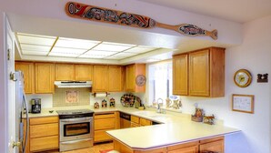 A kitchen with wooden cabinets, a central island with stools, a stove, and a refrigerator. - Christmas Cabin (Yosemite National Park)