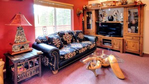 A cozy living room with a leather sofa, a glass coffee table, and wooden cabinets filled with decorative items. - Christmas Cabin (Yosemite National Park)