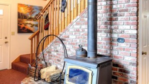 A room with a brick fireplace, a wooden staircase, and a painting on the wall. - Christmas Cabin (Yosemite National Park)