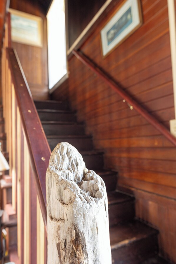 Un escalier en bois, avec une rampe et un poteau en bois au premier plan.
