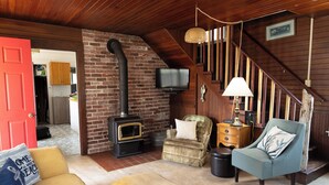 Una sala de estar acogedora con chimenea de ladrillo, televisor, sofá y sillón.