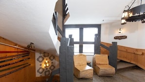Una escalera de madera con un banco de madera al final, un letrero que dice 'Snowflake Lounge' y una pared decorada con esquíes.